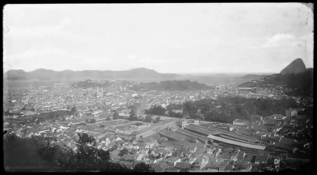 Cidade costeira com montanhas e complexo industrial.