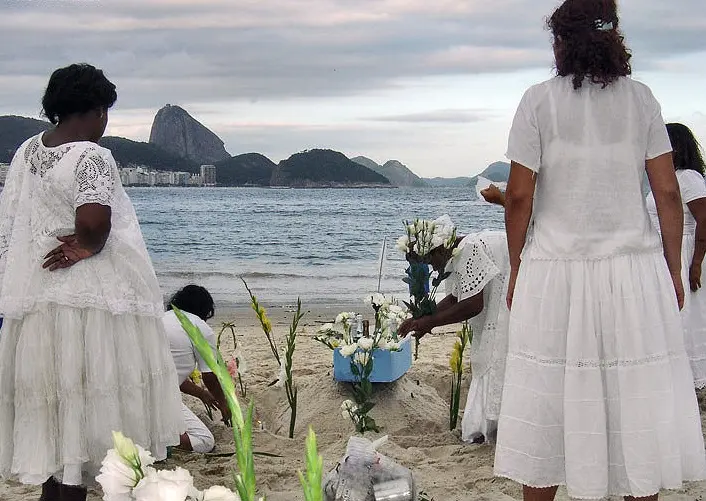 Cerimônia em praia com flores e mar calmo.