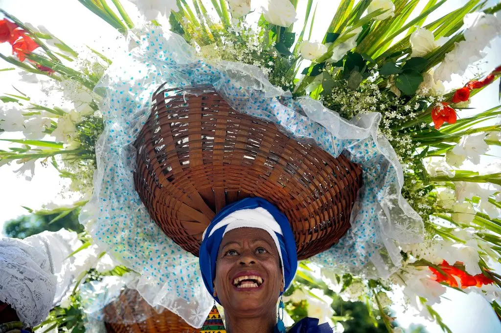 Mulher sorridente com cesto de flores brancas e vermelhas.