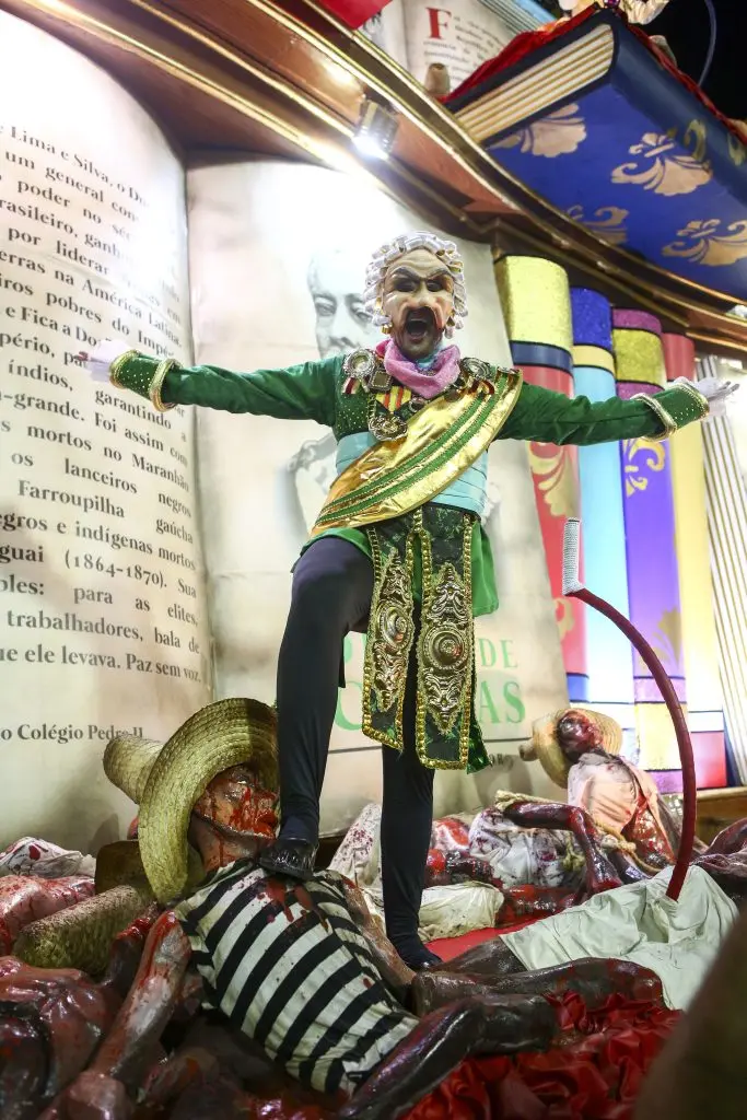 Carroça de Carnaval com figura central em trajes coloridos e detalhes metálicos.