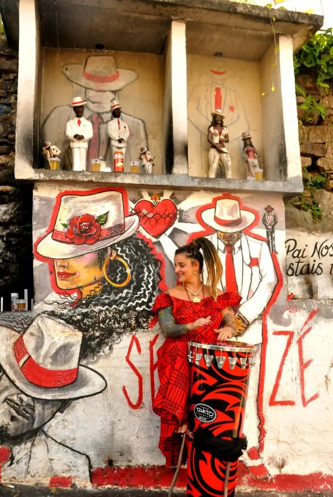 Muralha com estátuas formais e figura feminina com coração vermelho.