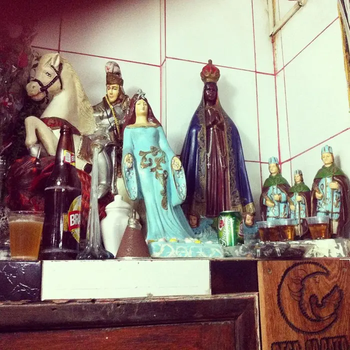 Altar doméstico com estátua de cavalo branco e figuras vestidas tradicionalmente.