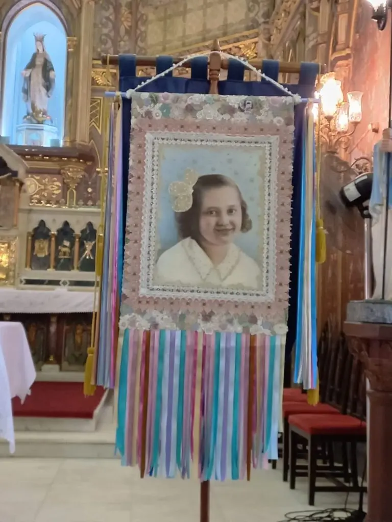 Menina sorridente pendurada em quadro religioso festivo.