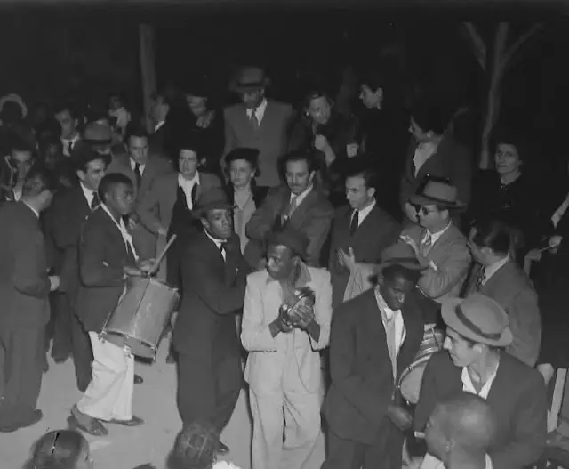 Grupo social em bar, com pessoas dançando e conversando.