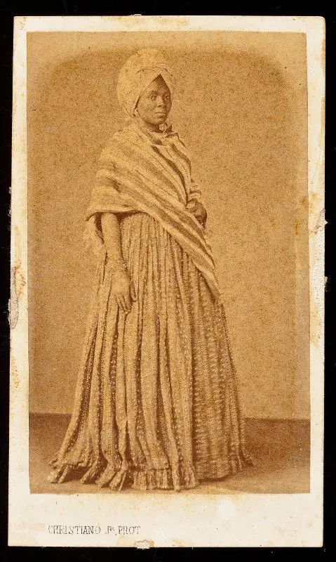 Escrava de ganho, fotografia de Christiano Junior, 1864-65, Museu Histórico Nacional. Em 1865, Christiano Júnior apresentou na Exposição Internacional do Porto a série “Photographias de costumes brazileiros”. O conjunto era formado por duas molduras, cada uma reunindo 12 fotografias de africanos e seus descendentes – a maioria, pessoas escravizadas – que trabalhavam nas ruas do Rio de Janeiro. Depois de exibidas, o fotógrafo deu as 24 imagens de presente ao  rei de Portugal, D. Fernando. Nas molduras, ainda é possível ler a dedicatória: “a. s. m. El Rei D. Fernando, Christiano Junior, Rua da Quitanda, 45, 2º andar”. Em 1933, essa coleção de fotos foi doada ao Museu Histórico Nacional.